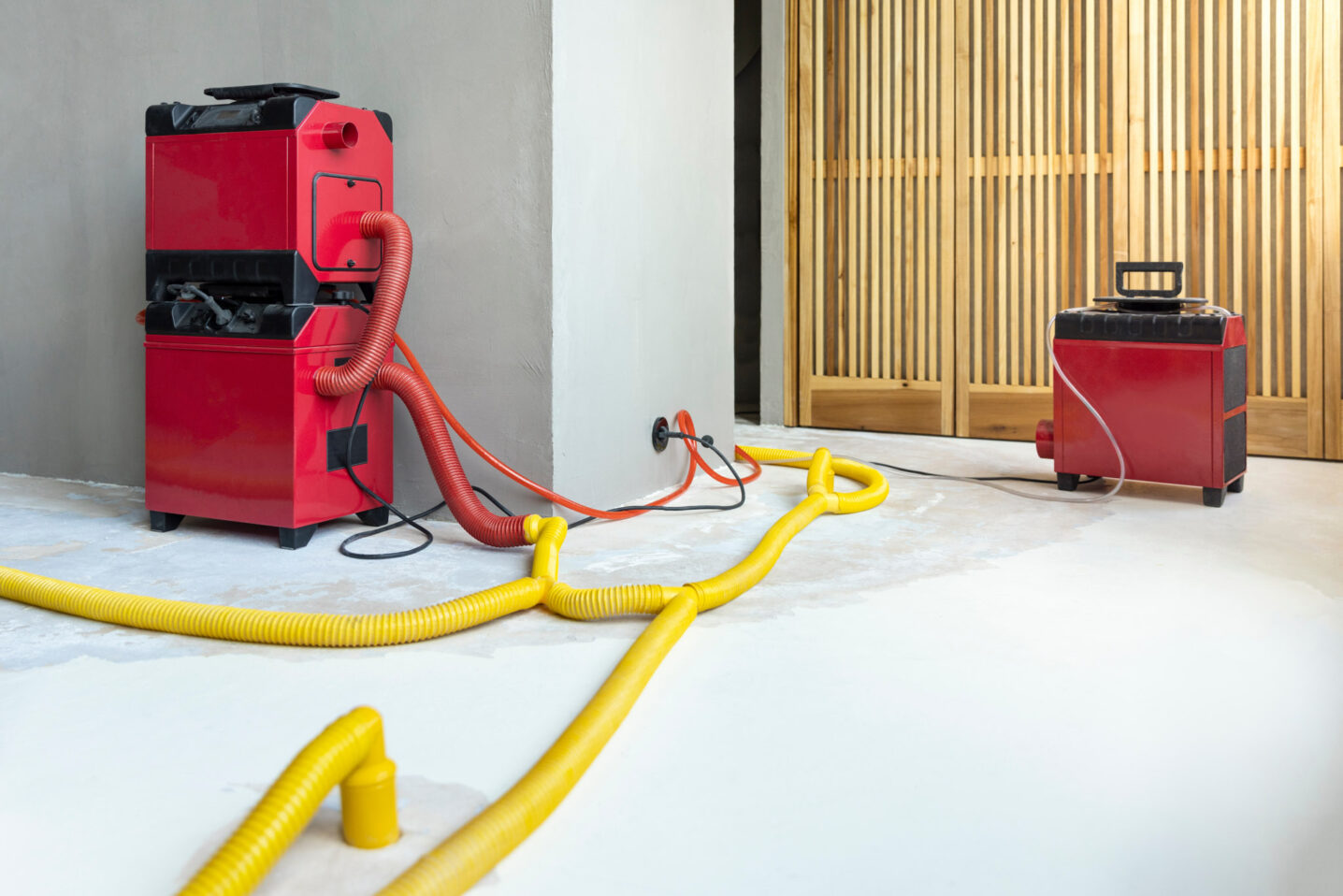 Water damage restoration service for a leaking home environment with industrial air movers, dehumidifiers and pipes to remove water and moist from the wet floor. Repair the house. Household insurance